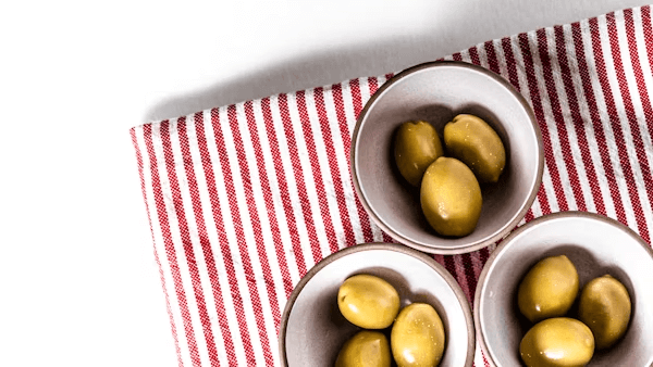 Three bowls of olives on red and white tablecloth
