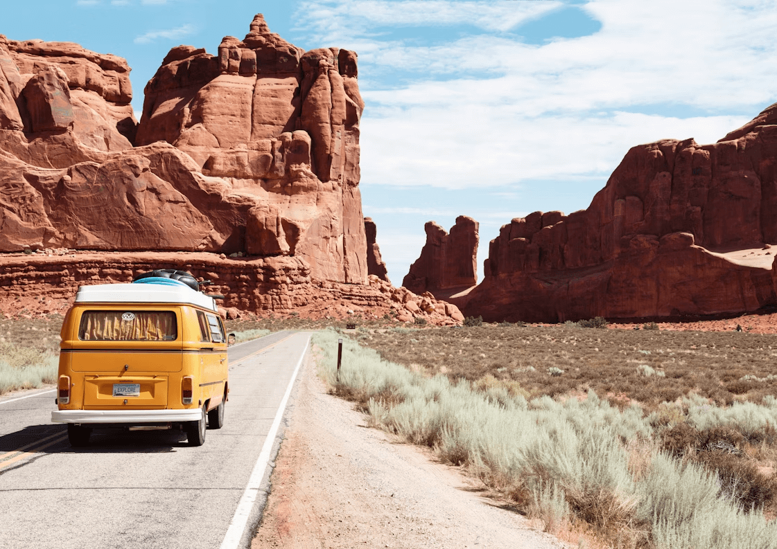 Yellow van driving on desert road representing campervan travel