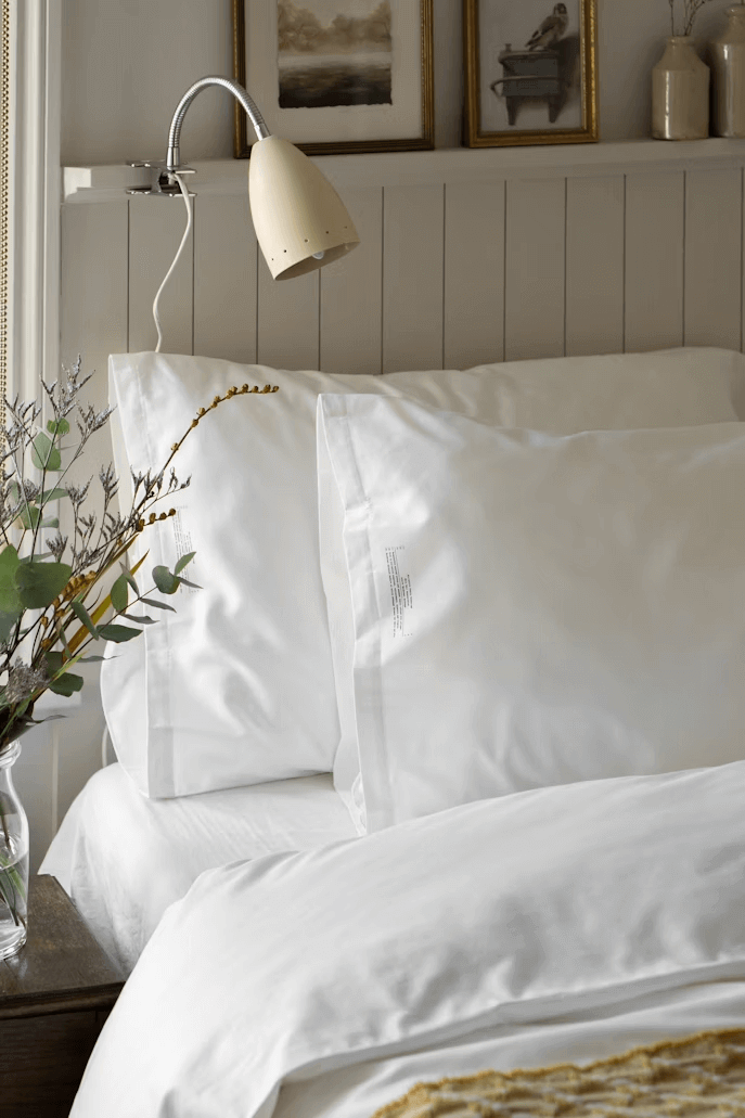 Bed with white sheets and vase of flowers