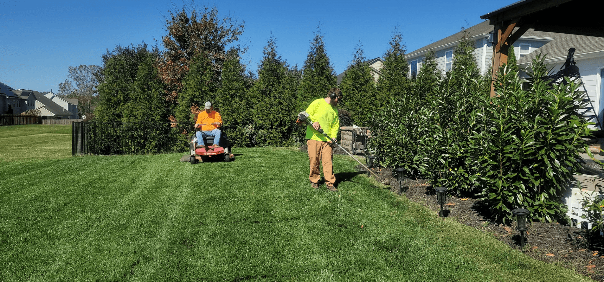 Man mowing a lawn with a kid- and