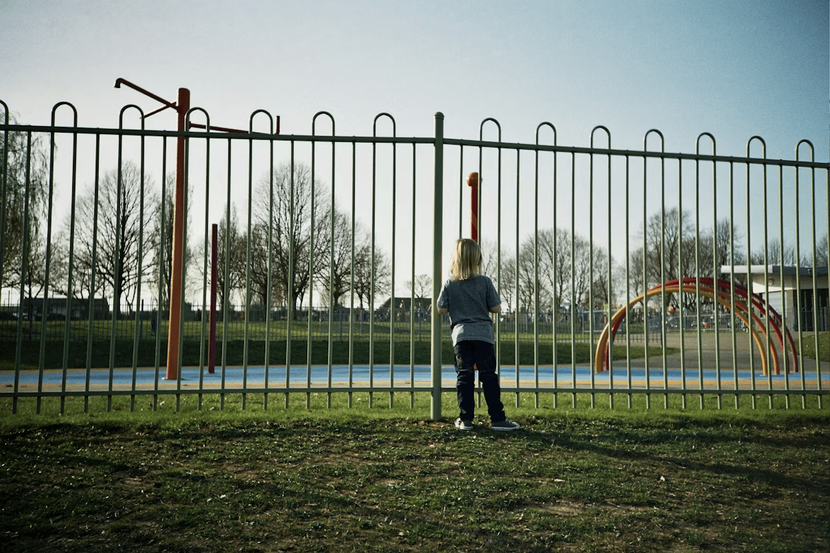 Person near metal fence, considering playground safety