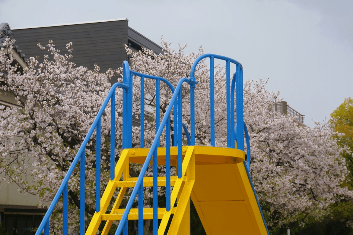 Yellow and blue backyard slide next to a tree,