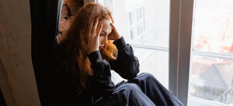 Woman sitting on window sill, looking