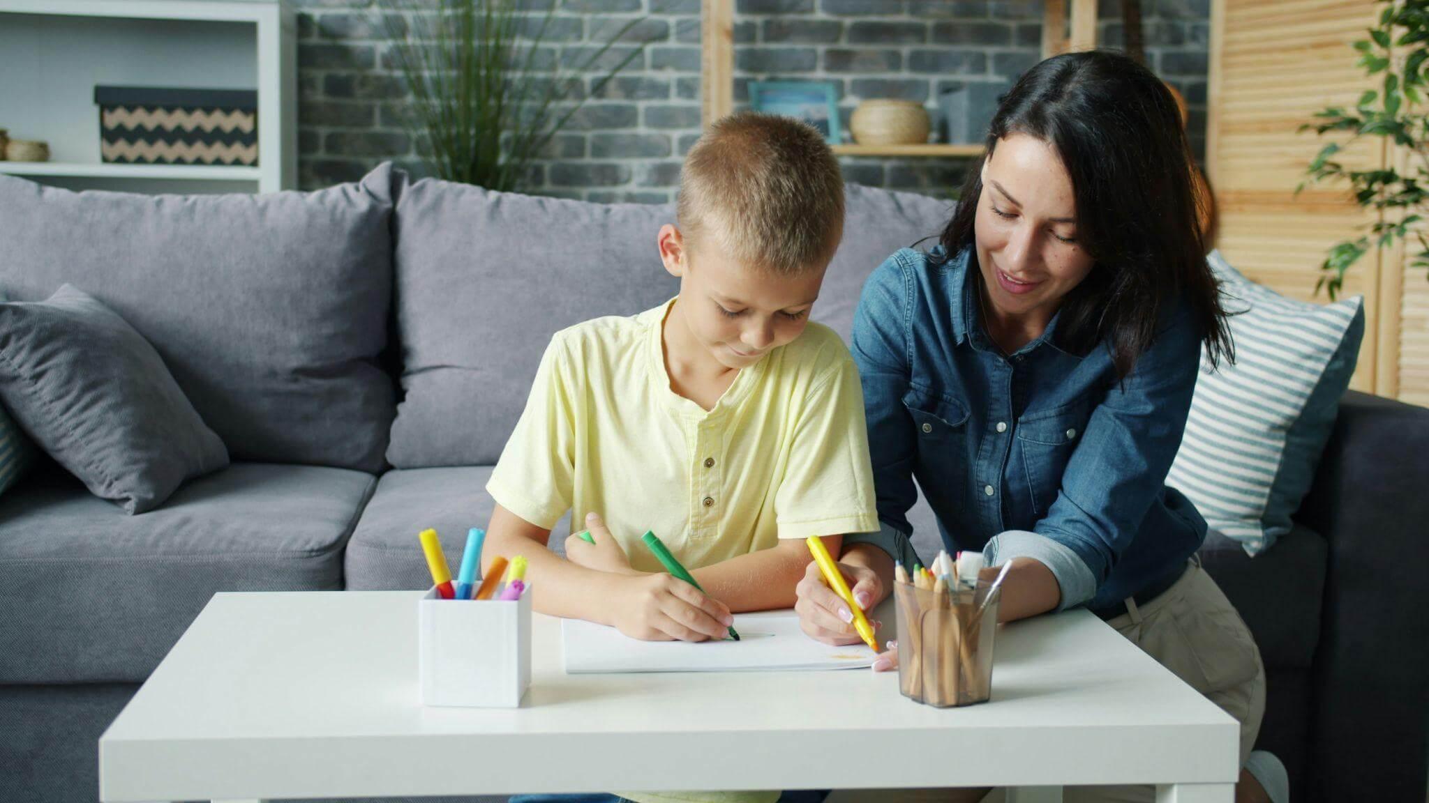 Woman teaching child communication skills with pencils at