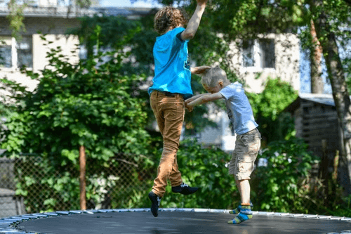 Two children jumping on a backyard trampoline