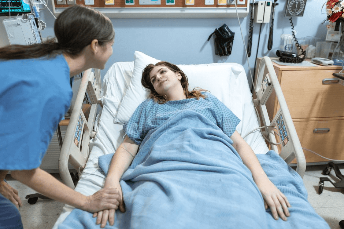 Two women in a hospital bed, discussing women