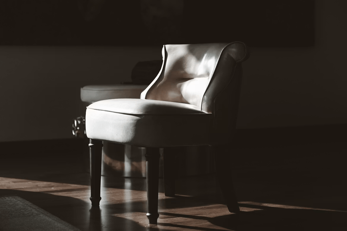 A white chair on a hardwood floor, representing
