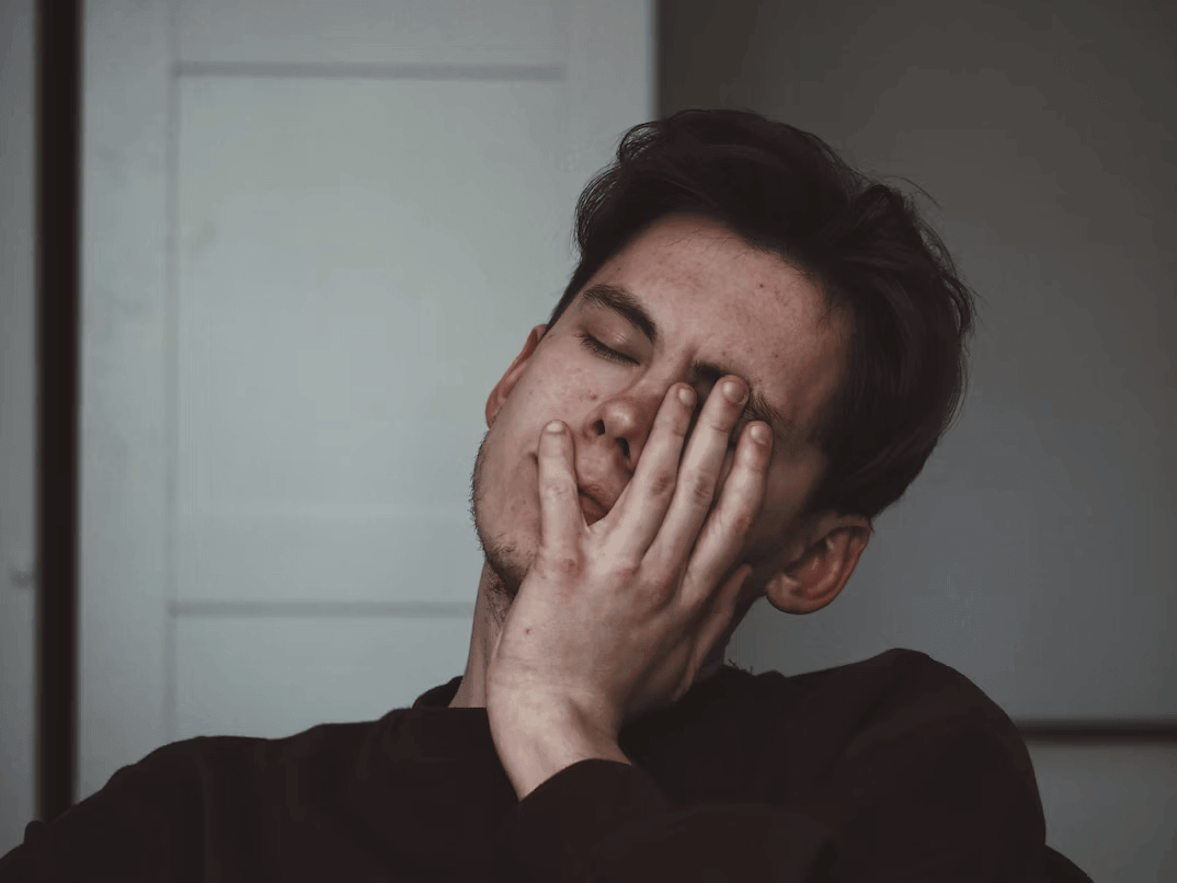 Man holding hands to his face, looking fatigued