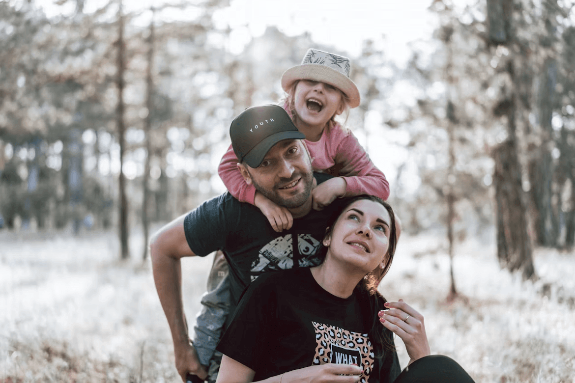 Man holds daughter on shoulders during family vacation