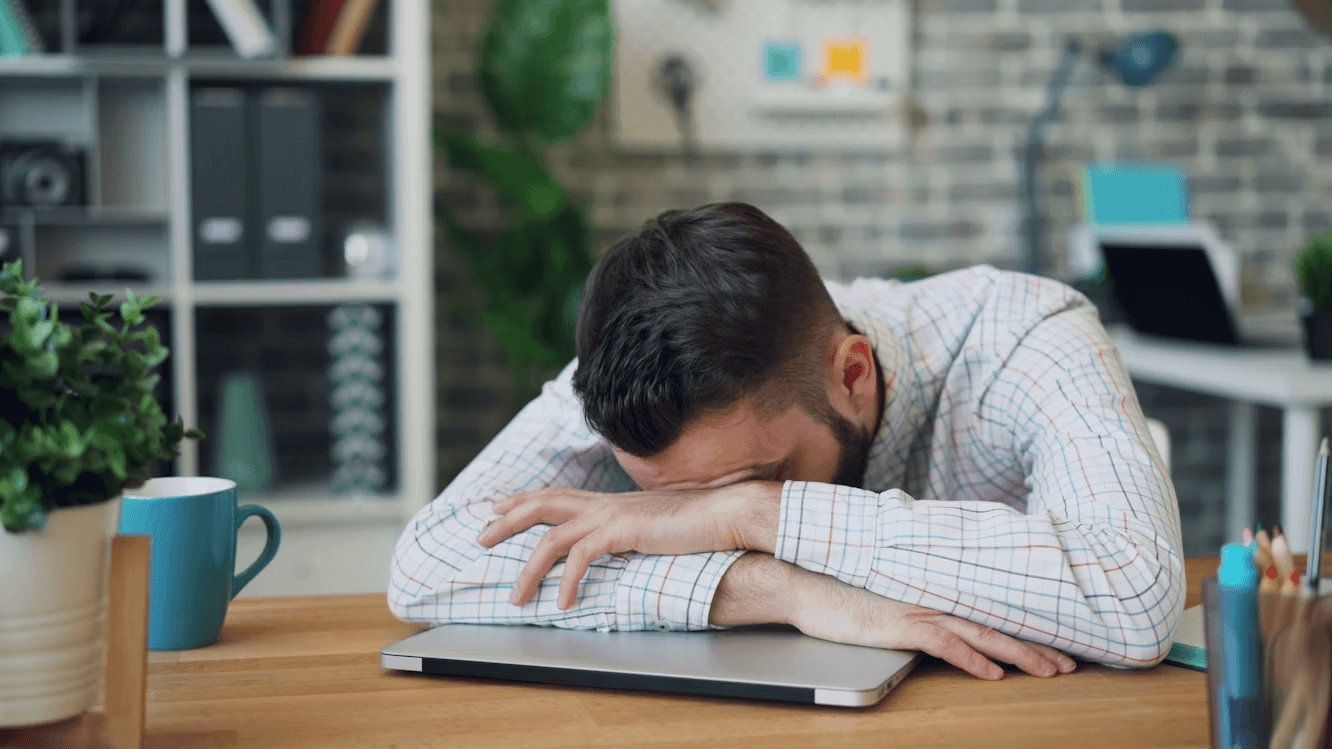 Man sitting at a desk with his head in his