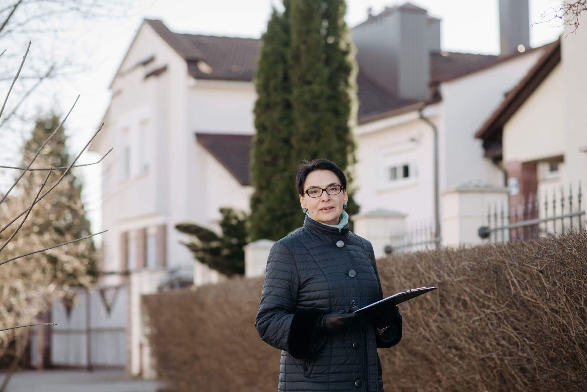 Woman holding clipboard in front of a house