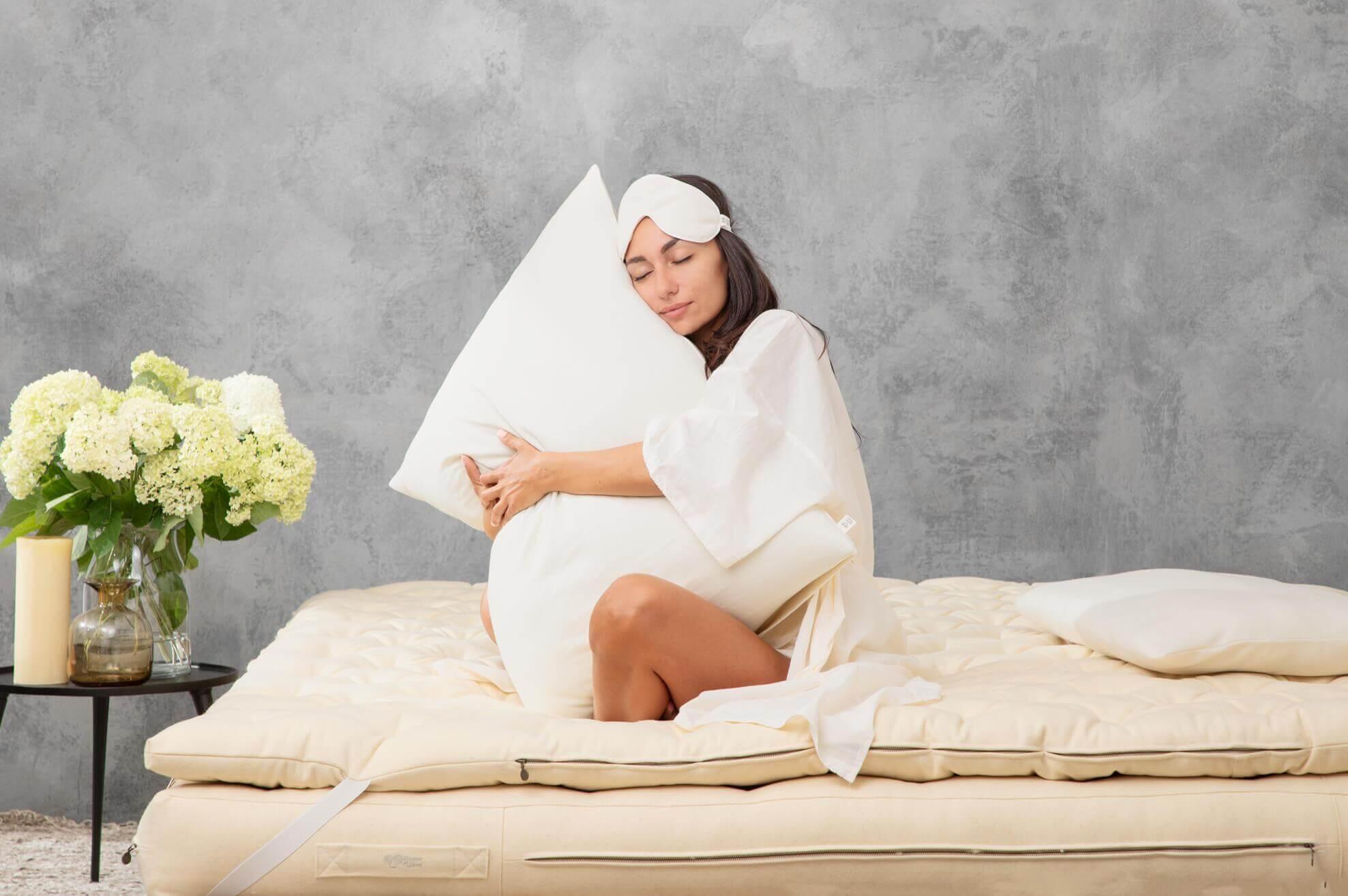 Woman on bed holding pillow, illustrating home comfort