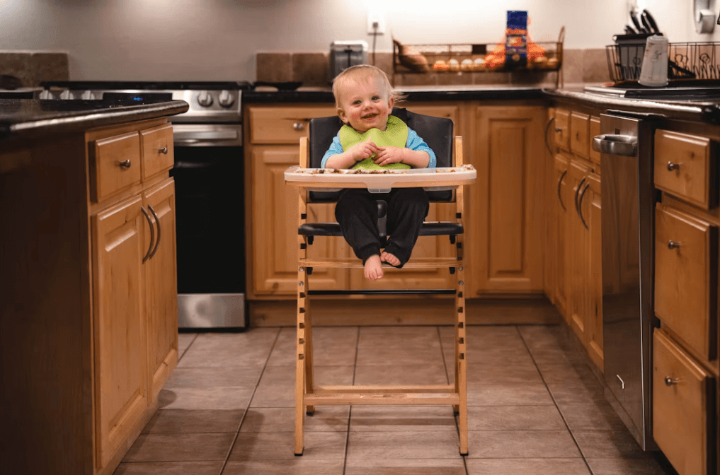 Baby in a wooden high chair in a modern kitchen