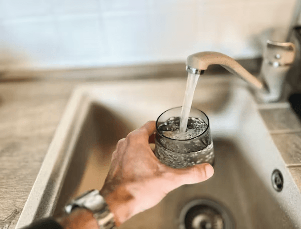 Person filling a glass with water from a