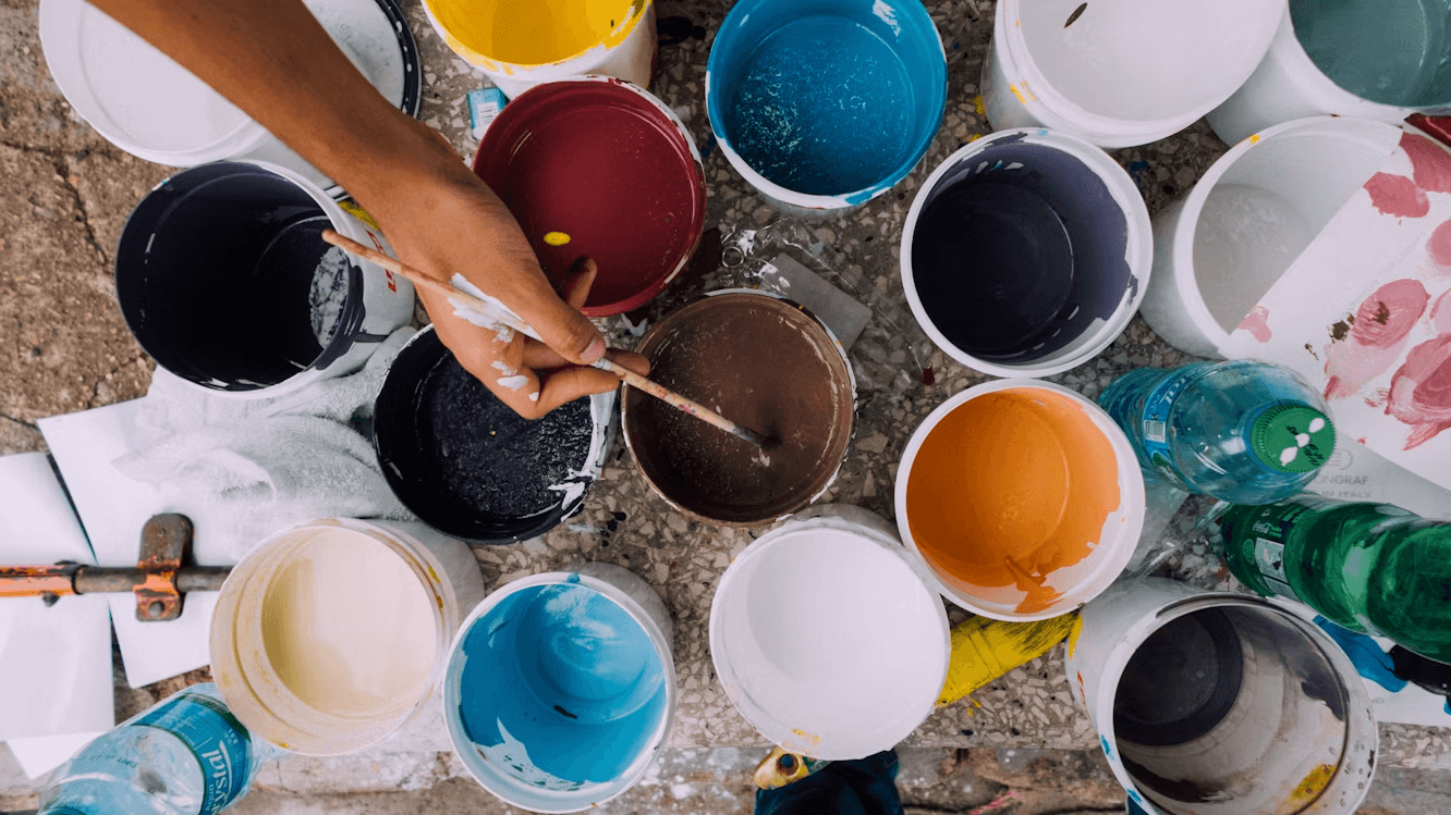 Professional painters holding paintbrushes and standing by paint