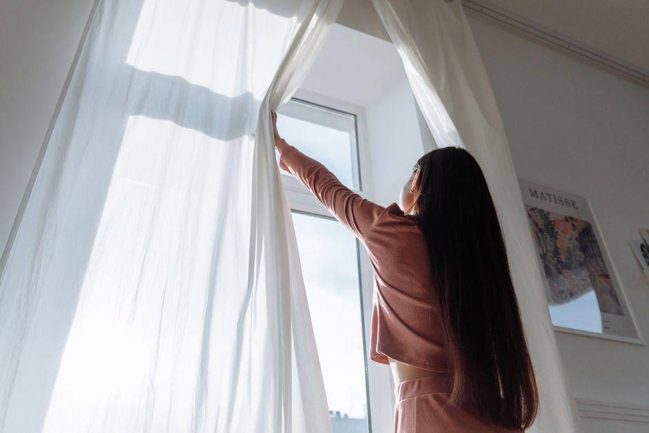 Woman holding a curtain in front of a window