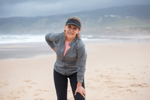 Woman standing on a beach, feeling relaxed and