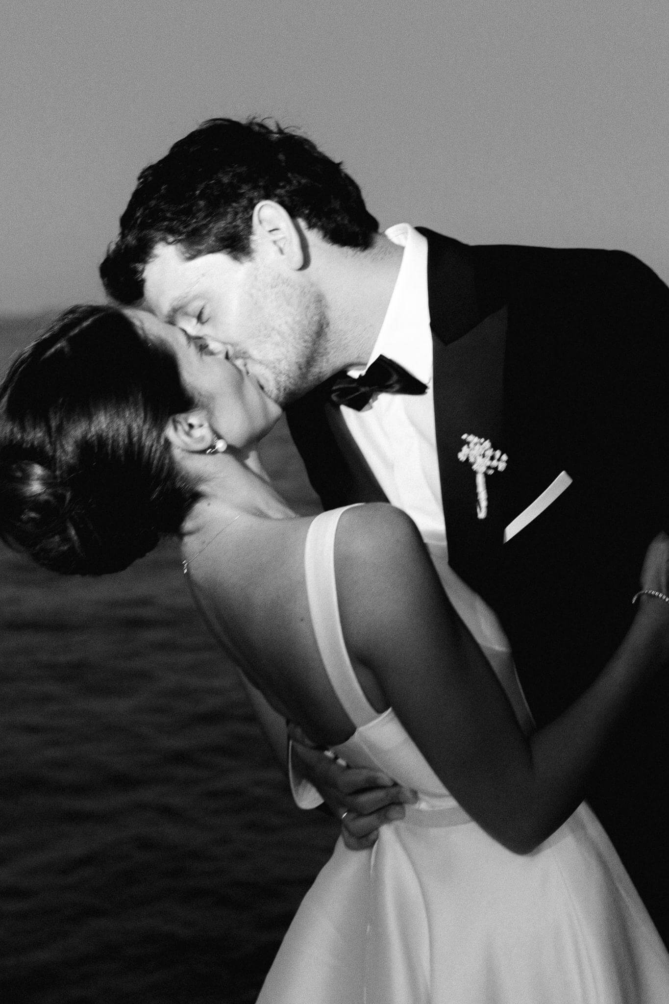Bride and groom kissing passionately by the ocean