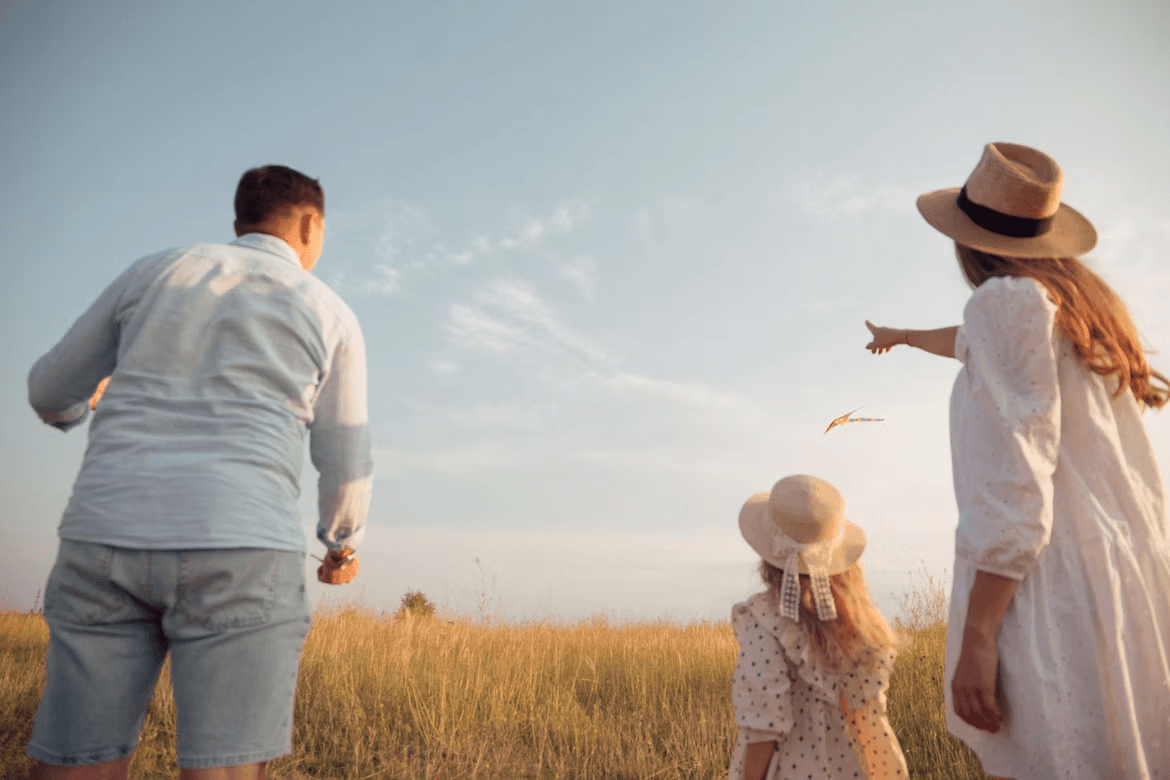 Family flying a kite together in a sunny field