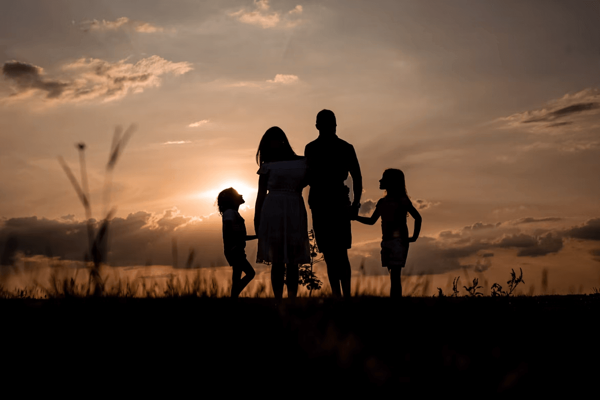 Family standing in a field at sunset for a late