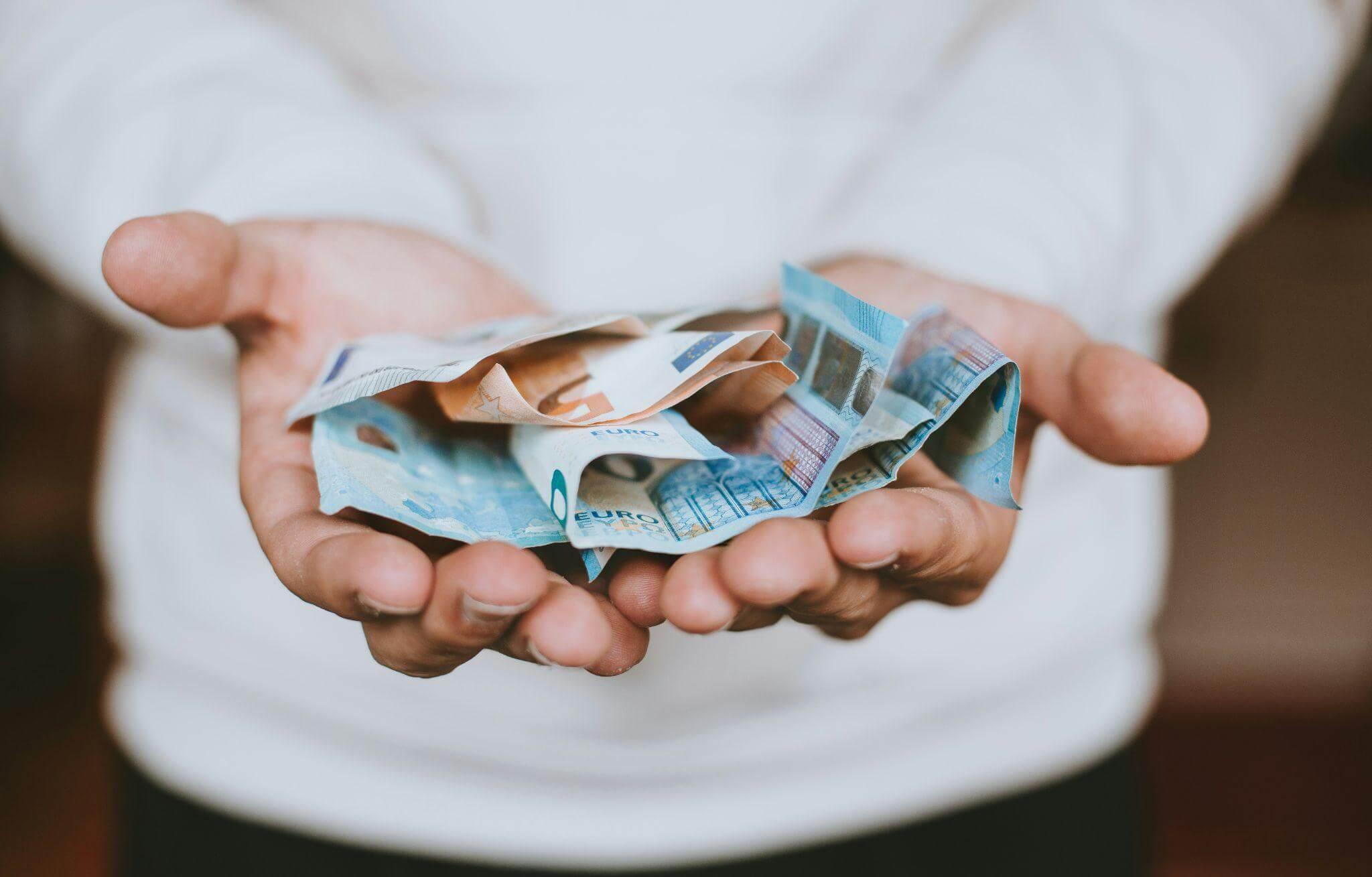 Person holding a bundle of money, representing a